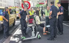  ?? PHOTO: NZME ?? A statistic . . . Ambulance and fire crews attend to a young woman who crashed a Lime E Scooter on Customs St in Auckland last week.