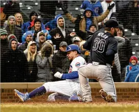  ?? DAVID BANKS PHOTOS / GETTY IMAGES ?? Chicago’s Kyle Schwarber (left) scored on a wild pitch from Peter Moylan (30) of the Braves as the Cubs overcame a 10-2 deficit.