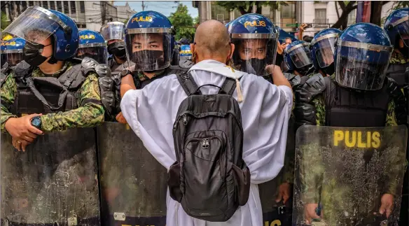  ?? ?? A Catholic priest talks to police officers standing guard as people take part in a protest against election results outside the Commission on Elections building in Manila, Philippine­s