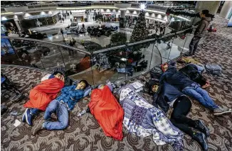  ?? JOHN SPINK / JSPINK@AJC.COM ?? Many travelers slept in the atrium on Dec. 18 at Hartsfield-Jackson Internatio­nal Airport the day after a massive power outage brought operations to a halt. Power was restored at the world’s busiest airport after the outage Dec. 17 that left planes and...