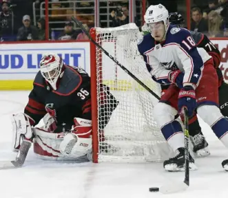  ?? Associated Press ?? Carolina goalie Curtis McElhinney keeps an eye on the puck as Columbus’ Pierre-Luc Dubois prepares to shoot in the first period. The Blue Jackets, who entered one point behind the Penguins in the Metropolit­an Division, lost to the Hurricanes, 4-2.