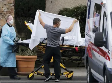  ?? ELAINE THOMPSON — THE ASSOCIATED PRESS ?? A staff member blocks the view as a person is taken by a stretcher to a waiting ambulance from a nursing facility where more than 50people are sick and being tested for the COVID-19virus, on Saturday in Kirkland, Wash.