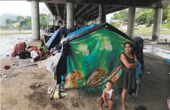  ?? Delmer Martinez / Associated Press ?? Residents of San Pedro Sula, Honduras, who were forced out their homes by flooding from two major hurricanes, shelter from the elements Saturday in makeshift tents beneath a highway.