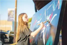  ?? Staff photo by Erin DeBlanc ?? ■ Kylee Johnson paints a brush stroke on a community canvas Friday during Downtown Live in Texarkana.