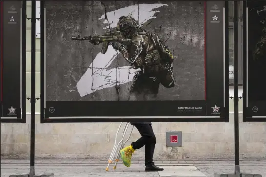  ?? DMITRI LOVETSKY — THE ASSOCIATED PRESS ?? A man in St. Petersburg, Russia, walks past a street exhibition of military posters named “We bring Peace,” dedicated to the military operation in Ukraine, this month.