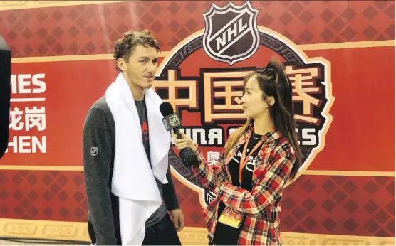  ??  ?? Matthew Tkachuk chats with a member of Chinese media after Friday’s practice in Shenzhen, China. The Flames were scheduled to play the Bruins today.