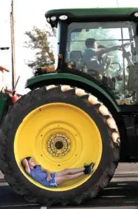  ?? Ronald W. Erdrich photos/The Abilene Reporter-News via AP ?? left
Jaci Welsh, 7, reclines in the wheel as Jared Hernandez, 8, pretends to drive the tractor with his friend Bobby Rangel, 6, on
April 4 at Snyder’s Calvary Baptist Church.