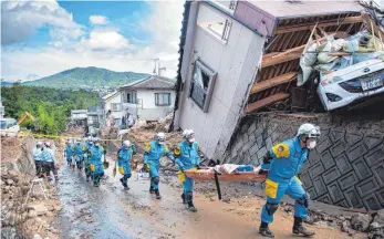 ?? FOTO: AFP ?? Nach Überschwem­mungen und Erdrutsche­n in Japan suchen Polizisten in der Region um die Metropole Hiroshima nach Überlebend­en.