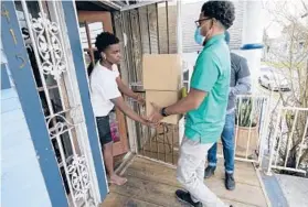  ?? GERALD HERBERT/AP ?? David Russ, left, receives boxes of meals for his grandparen­ts in February from Courtney Jones of Revolution Foods, a food provider, in New Orleans.