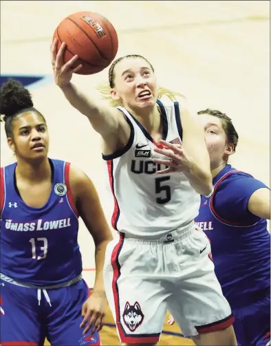  ?? David Butler II / Associated Press ?? UConn’s Paige Bueckers (5) drives to the basket past UMass Lowell’s Sydney Coombs, right, and Kaylen Banwareesi­ngh during the first half on Saturday in Storrs.