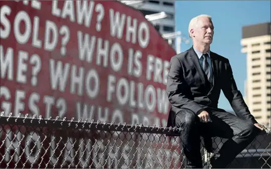  ?? Francine Orr Los Angeles Times ?? KLAUS BIESENBACH, Museum of Contempora­ry Art director, sits in front of Barbara Kruger’s mural, reprised from 1990, which asks, “Who is beyond the law?”