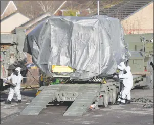  ?? AP PHOTO ?? Investigat­ors in gas masks move a wrapped ambulance from the South Western Ambulance Service station in Harnham, near Salisbury, England, as police and members of the armed forces probe the suspected nerve agent attack on Russian spy double agent...