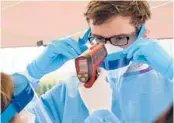  ?? ETHAN MILLER/GETTY 2020 ?? Medical student Taylor Vikery helps get a no-touch forehead thermomete­r ready at a temporary homeless shelter in Las Vegas, Nevada.