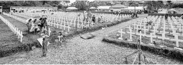  ?? — AFP photo ?? Residents visit the graves of relatives at the mass grave for victims of Super Typhoon Haiyan during the fifth anniversar­y of the typhoon in Tacloban City, Leyte province, central Philippine­s.