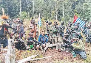  ?? REUTERS ?? A man who is identified as Philip Mehrtens, the New Zealand pilot who is said to be held hostage by a rebel group, sits among the separatist fighters in Indonesia’s Papua region on Monday.