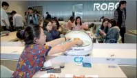  ?? PROVIDED TO CHINA DAILY ?? A diner collects her meal from a delivery robot at the National Exhibition and Convention Center (Shanghai).