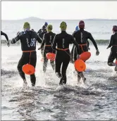  ??  ?? Swimmers run into the water at the start of the open water session in Rosses Point.