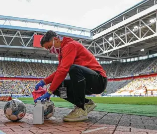  ?? Sascha Schuermann / Associated Press ?? Soccer balls are disinfecte­d during the Bundesliga match Saturday between host Duesseldor­f and Paderborn at the empty Merkur Spiel-Arena. Even with no fans, sports are still worth watching.