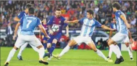  ?? AP ?? Barcelona's Lionel Messi is challenged by Malaga players during their La Liga match on Saturday.
