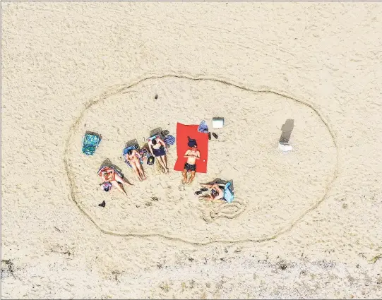  ?? Patrick Sikes / For Hearst Connecticu­t Media ?? A family carves out some space in the sand at Cove Island Park in Stamford on May 5, observing social distancing during the COVID-19 pandemic.