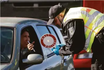  ?? Jean-Francois Badias / Associated Press 2020 ?? A German police officer checks authorizat­ion for a woman to enter the country in Kehl, Germany in 2020. Visitors to Germany will not have to show proof of vaccinatio­n this summer.