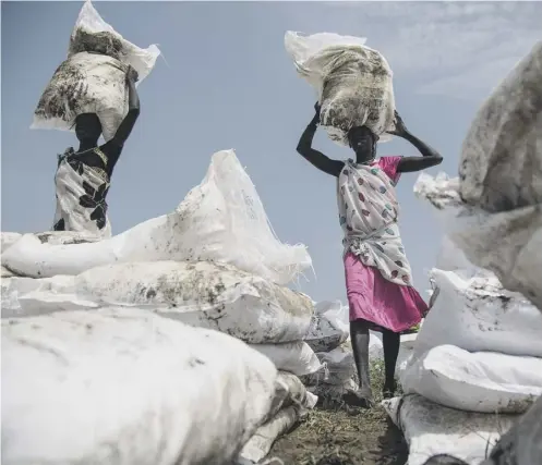  ??  ?? Women carry sacks of food airdropped by the World Food Programme and distribute­d by Oxfam near Lankien, South Sudan