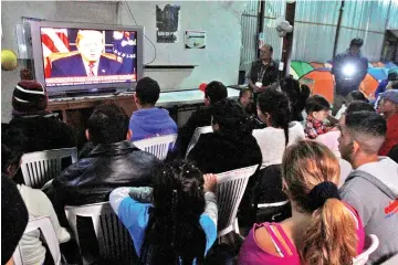  ??  ?? Migrants, part of a caravan of thousands from Central America trying to reach the United States, watch Trump’s televised address to the nation at the ‘Juventud 2000’ shelter in Tijuana, Mexico. —Reuters photo