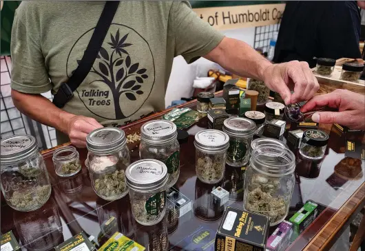  ?? (File Photo/AP/Richard Vogel) ?? A vendor with Talking Trees Farms, a Northern Humboldt County sustainabl­e cannabis farm, offers a taste of their latest crop June 20, 2019, to an attendee of WeedCon West 2019 in Los Angeles.