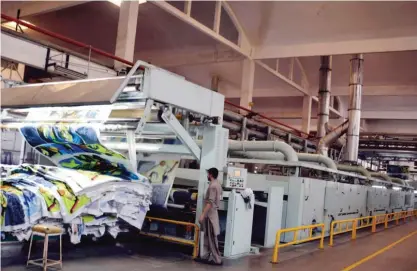  ?? — AFP ?? FAISALABAD: A Pakistani worker operates a machine at a textile factory in Faisalabad.