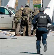  ?? AP ?? Royal Canadian Mounted Police officers prepare to take a suspect into custody at a petrols station in Enfield, Nova Scotia.