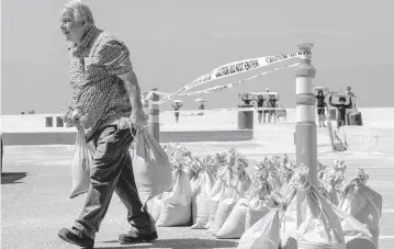  ?? ALLEN J. SCHABEN Los Angeles Times ?? John Straub, left, a volunteer with West Orange County Community Emergency Response Team loads dozens of sandbags for local residents to fortify their homes ahead of anticipate­d high surf, strong winds and flooding from the approachin­g Hurricane Hilary in Seal Beach on Friday.