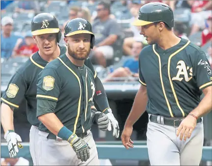  ?? MIKE STONE — THE ASSOCIATED PRESS ?? The A’s Jonathan Lucroy, center, is congratula­ted by Mark Canha, right, and Matt Olson after hitting a grand slam in Monday’s romp.