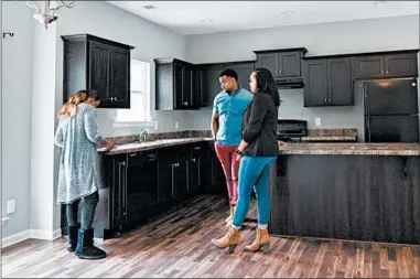  ?? CAMERON CARNES/FOR THE WASHINGTON POST ?? Astardii and Rick Hopkins, right, look at a home’s kitchen with Realtor Mishae Dickerson.