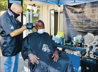  ?? JUDITH PRIEVE — STAFF PHOTOGRAPH­ER ?? Octavio Perez of Brentwood’s Bold Barber cuts Terry Huggins’ hair on Tuesday behind the Community Outreach Center as part of the new Oasis Project, a joint effort of the White Pony Express and SHARE Community nonprofits to bring homeless services to the area.