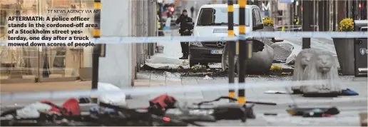  ?? TT NEWS AGENCY VIA AP ?? AFTERMATH: A police officer stands in the cordoned-off area of a Stockholm street yesterday, one day after a truck mowed down scores of people.
