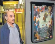  ?? AFP/FILE ?? Mehran Karimi Nasseri passes by the poster of the movie inspired by his life, at Paris airport on August 12, 2004.