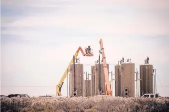  ??  ?? Workers install infrastruc­ture for separating oil, gas and so-called produced water, a waste product from fracking operations.