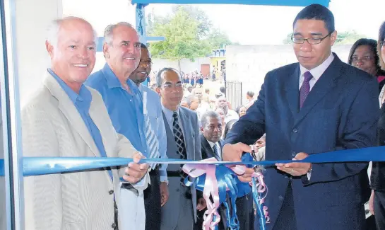  ?? FILE PHOTOS ?? 2009: Minister of Education, Andrew Holness (right) cuts the ribbon to officially open the over $30million