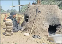  ??  ?? A labourer baking bread in a mud oven in Luxor, Egypt