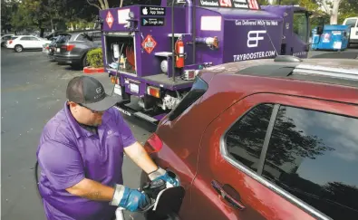  ?? Paul Chinn / The Chronicle ?? Cesar Guzman, a Booster mobile refueler, fills the gas tank of a car in the Technology Credit Union parking lot.