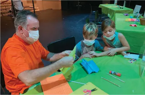  ?? Byron Tate) (Pine Bluff Commercial/ ?? Michael Turley, an education program coordinato­r at The Generator, helps Tynes East (10) and Madison East (6) of Benton, fold paper airplanes at Tinkerfest.