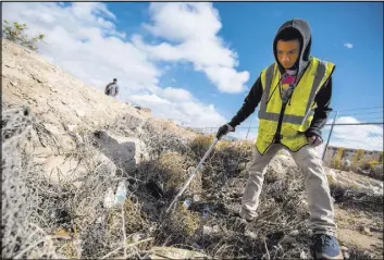  ?? VEGAS REVIEW-JOURNAL ?? Naphon Meesiri picks up garbage Saturday during the cleanup of the newly acquired UNLV site off of Tropicana Avenue east of Koval Lane. More than 150 volunteers registered for the event and spent three hours picking up trash and debris.