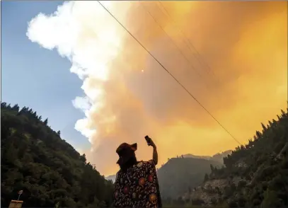  ?? NOAH BERGER — THE ASSOCIATED PRESS ?? Jessica Bell takes a video as the Dixie Fire burns along Highway 70in Plumas National Forest on Friday.