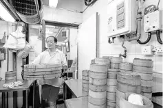  ?? — Pictures by Anthony Wallace ?? A kitchen worker carries bamboo dim sum steamers at the Lin Heung Tea House.