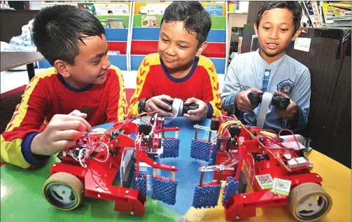  ?? AHMAD KHUSAINI/JAWA POS ?? TIM JAGOAN: Dari kiri, Samir, Gielang, dan Raditya mengoperas­ikan robot transporte­r di Perpustaka­an SD Muhammadiy­ah 11 kemarin (11/4).