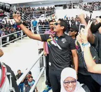  ?? — IBRAHIM MOHTAR/ The Star ?? Say cheese:
Youth and Sports Minister Khairy Jamaluddin (centre) taking photograph­s of the SEA Games volunteers at the National Hockey Stadium in Bukit Jalil yesterday.