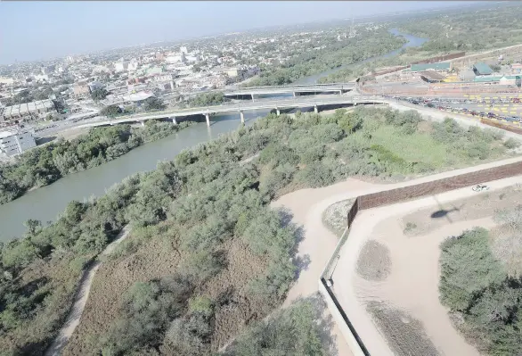  ?? JOHN MOORE/ GETTY IMAGES ?? A U.S. Customs and Border Protection helicopter patrol flies over a border fence by a bridge between the U.S. and Mexico in Hidalgo, Texas.