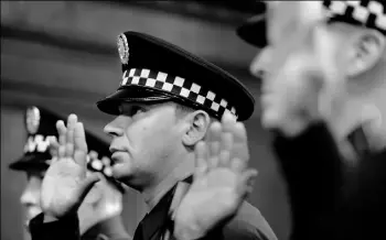  ?? Rebecca Droke/Post-Gazette ?? Timothy Novosel, center, is sworn in as a Pittsburgh police sergeant Monday during a promotion ceremony at the City-Council Building, Downtown. He was one of seven city officers promoted Monday.