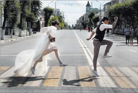  ?? Frank Augstein ?? Newlyweds pose Sunday on a crossing for wedding photograph­ers during World Cup festivitie­s in Samara, Russia. The Associated Press