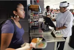  ?? AMY BETH BENNETT/STAFF PHOTOGRAPH­ER ?? Food service worker Lisa Hayes rings up a student in the cafeteria at Santaluces High School in Lantana. Lunch in Palm Beach County costs $2.30.